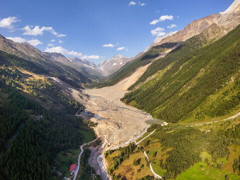 Aerial view of the contrasting textures of the rugged mountains meeting the soft green forests in the valley, Blatten, Wallis, Switzerland.