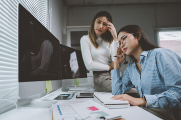 Businesswomen feeling stressed while working with stock market charts on computer