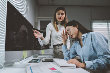 Businesswomen discussing negative financial report on computer screen