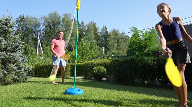 Family plays swingball, tetherball in their sunny backyard, enjoying summer fun, recreation and bonding