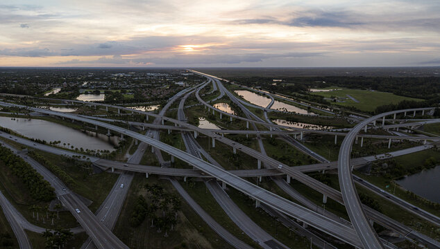 Aerial view of the complex sawgrass highway interchange system as it cuts through the landscape, connecting roads and reflecting the soft glow of the sky, Sunrise, Florida, United States.