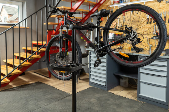 Bicycle in home garage workshop on stand surrounded by tools and equipment