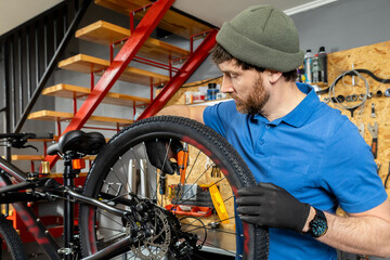 Mechanic in blue shirt adjusting bicycle rear wheel with precision in indoor garage