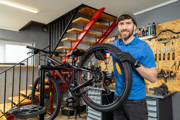 Mechanic in blue shirt adjusting bicycle rear wheel with precision in indoor garage