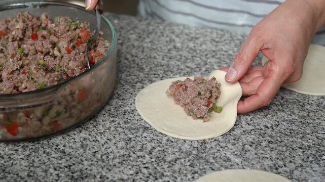 Woman filling and closing homemade fatayers