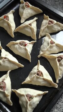 Middle Eastern savory hand pies ready to bake on a baking tray. Homemade fatayers.