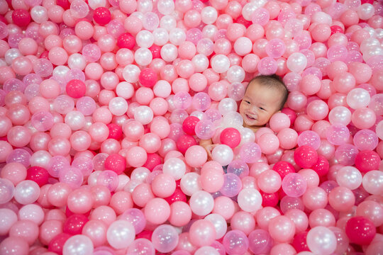 Baby enjoy playtime in pink ball pit - Powered by Adobe