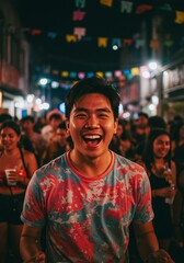Fototapeta premium Joyful young man grins broadly amidst a vibrant night street festival, surrounded by a lively crowd and colorful decorations, embodying pure happiness and celebration