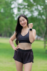 Fototapeta premium Young asian sportswoman showing her smartwatch in a park