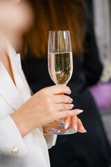 woman holding glass of white wine on the blurred background. close up
