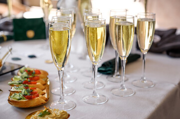 glasses of champagne on a white table in a banquet hall.