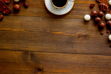 Chocolate pieces and coffee on wooden desk top view frame - set of sweets - copy space