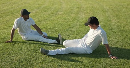 Starting stretch, diverse male cricketers in white kit massaging ankles, talking on grassy outfield