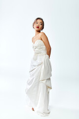 Fototapeta premium Elegant young bride in white dress posing gracefully in a serene studio setting