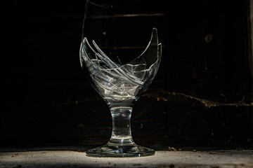 Broken wine glass with shattered pieces inside on a dark blue background