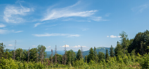 A sweeping view of lush mountains under a bright blue sky with wispy clouds, perfect for travel ads, outdoor gear, or nature-inspired branding