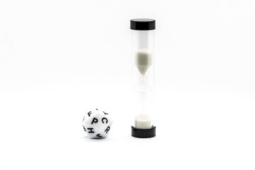 Close-up of an hourglass and letter dice used in board games, isolated on a white background, representing time, word challenges, and educational play.