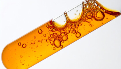 Bubbles forming inside test tube with orange fluid on white background. Laboratory chemistry.