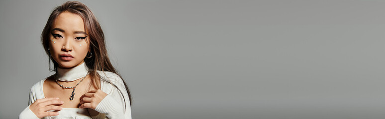 Stylish young asian woman showcases fashion elegance in modern studio setting