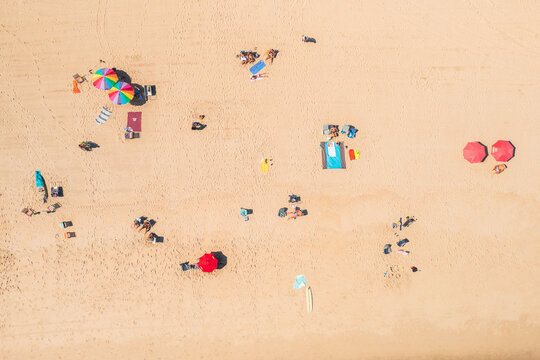 Aerial view of sunbathers and colorful umbrellas dotting the sandy expanse of the beach, creating a vibrant tapestry of leisure, Long Beach Island, New Jersey, United States.