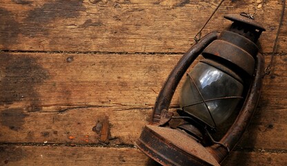 Kerosene lamp on a shabby wooden floor. Wooden floor background. Antique lamps, rust, close up. Extremely dark background, brown color. Gloomy, dark photo, copy space