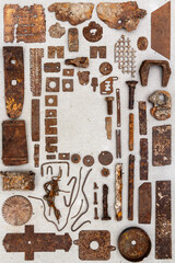 A group of various old rusty bits and pieces arranged on a concrete surface. Old rusty nuts, bolts, nails and other parts flay lay on gray background.