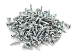Pile of metal self-tapping screws on white background