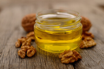 Glass jar of walnut oil with walnuts on rustic wooden table