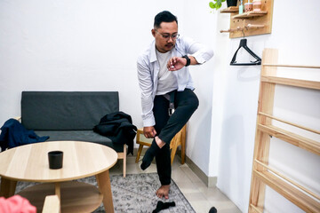 Man Hurriedly Puts On Socks While Checking Time On Smartwatch