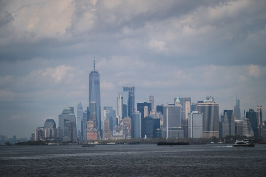 View of striking skyscrapers puncturing the skyline, standing as monuments against a backdrop of moody skies and tranquil waters, New York, New York, United States.