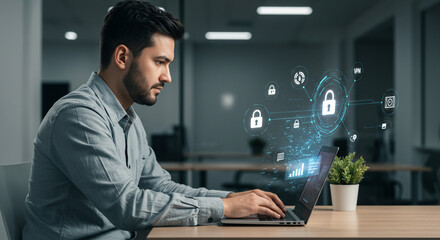 Man working on laptop with digital security overlay in a modern office environment with plant decor