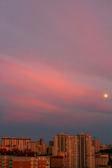 Fototapeta premium Bright sky at sunset, clouds, warm colors almost red, moon and houses