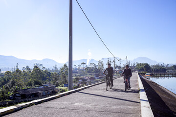 Friends Cycling by a Serene Lake, Chatting While Cycling in the Beautiful Countryside