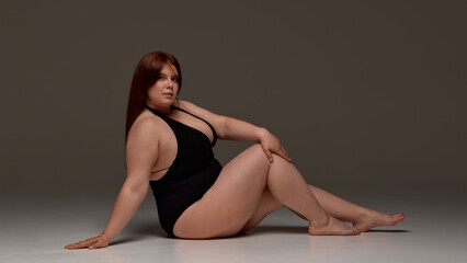 A plus-size model confidently poses in black swimwear, embodying body positivity and self-acceptance. Concept of embracing diversity and promoting confidence.