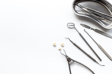 Many dental metal tools and teeth crows for implantation on white background. Professional Dentist desktop, top view