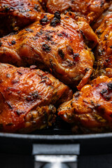 Baked chicken thighs on a cast iron grill pan with a crispy crust