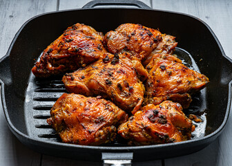 Baked chicken thighs on a cast iron grill pan with a crispy crust