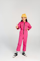 Trendy preteen girl in pink overalls poses confidently for kids fashion