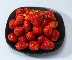 Juicy seasonal strawberries close up macro texture on a black plate