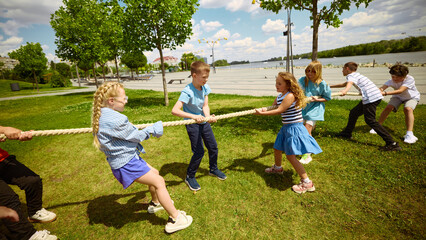 Children engage in a lively game of tug-of-rope in a sunny park setting concept of childhood play. Idea of outdoor competition and child growth.