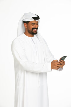 Portrait of an emirati man on a white background using mobile.