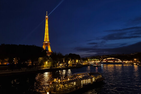 Paris, France, August 3, 2025: Eiffel Tower at Night with Illuminated River Seine Cruise for Travel and Tourism