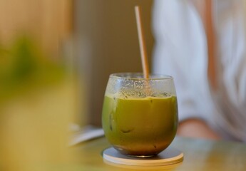 Iced Green Matcha Latte in Glass with Bamboo Straw On Table