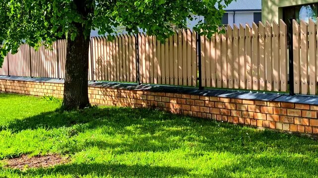 Wooden Plank Fence On A Brick Stone Base In The Yard. Static Shot