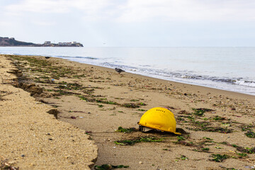 Obraz premium yellow lifeguard helmet on the sandy beach on a cloudy day near Marmara sea