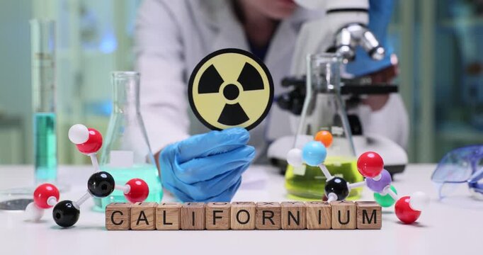 A scientist conducts research on californium, showcasing molecular models and lab equipment used in the field