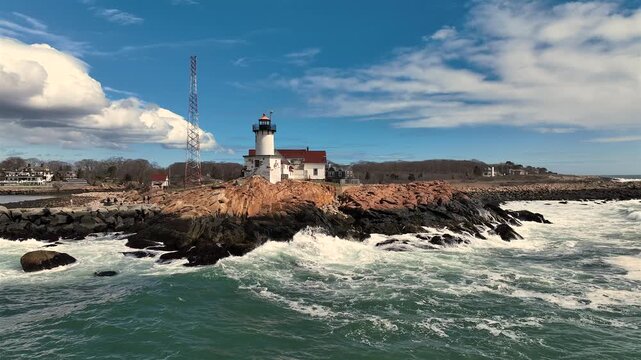 Aerial view of the Eastern Point Lighthouse atop a rocky outcrop, where the waves crash against the rugged coastline, Gloucester, Massachusetts, United States.
