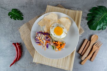 Traditional Indonesian Fried Rice with Egg Served on White Plate with Pickles and Crackers