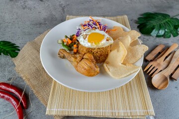 Traditional Indonesian Chicken Fried Rice Served on White Plate with Pickles and Crackers