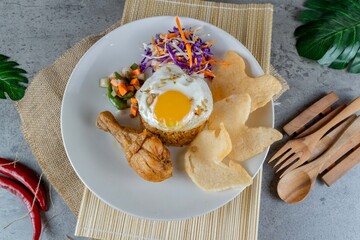 Traditional Indonesian Chicken Fried Rice Served on White Plate with Pickles and Crackers